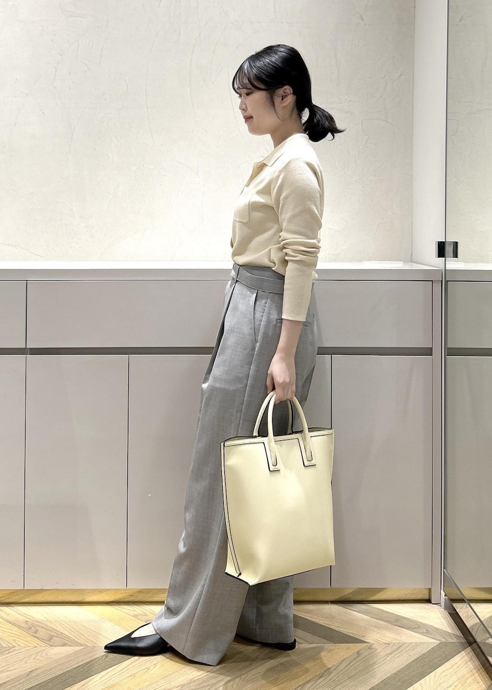 ブラック系のパンプス、ホワイト系のトートバッグ、グレー系のその他パンツを着用したレディースの冬コーディネートの2枚目の写真