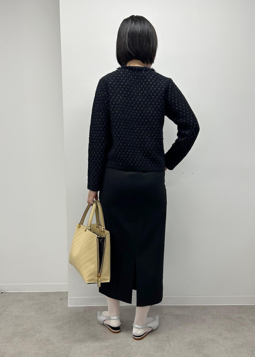 シルバー系のパンプス、ベージュ系のトートバッグ、ブラック系のスカートを着用したレディースの秋コーディネートの3枚目の写真