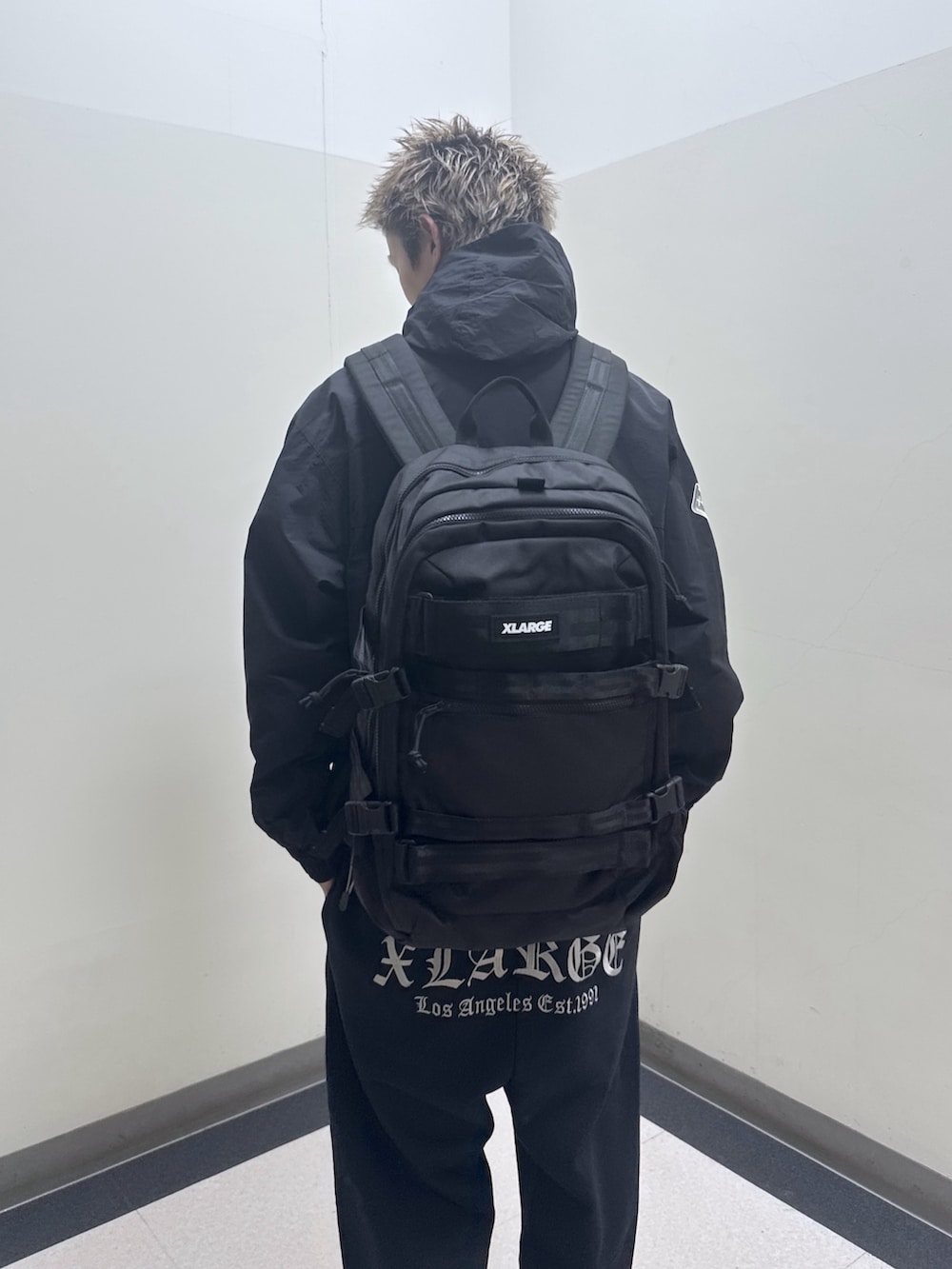 ブラック系のナイロンジャケット、ブラック系のバックパック/リュック、ブラック系のスウェットパンツを着用したメンズの冬コーディネートの6枚目の写真