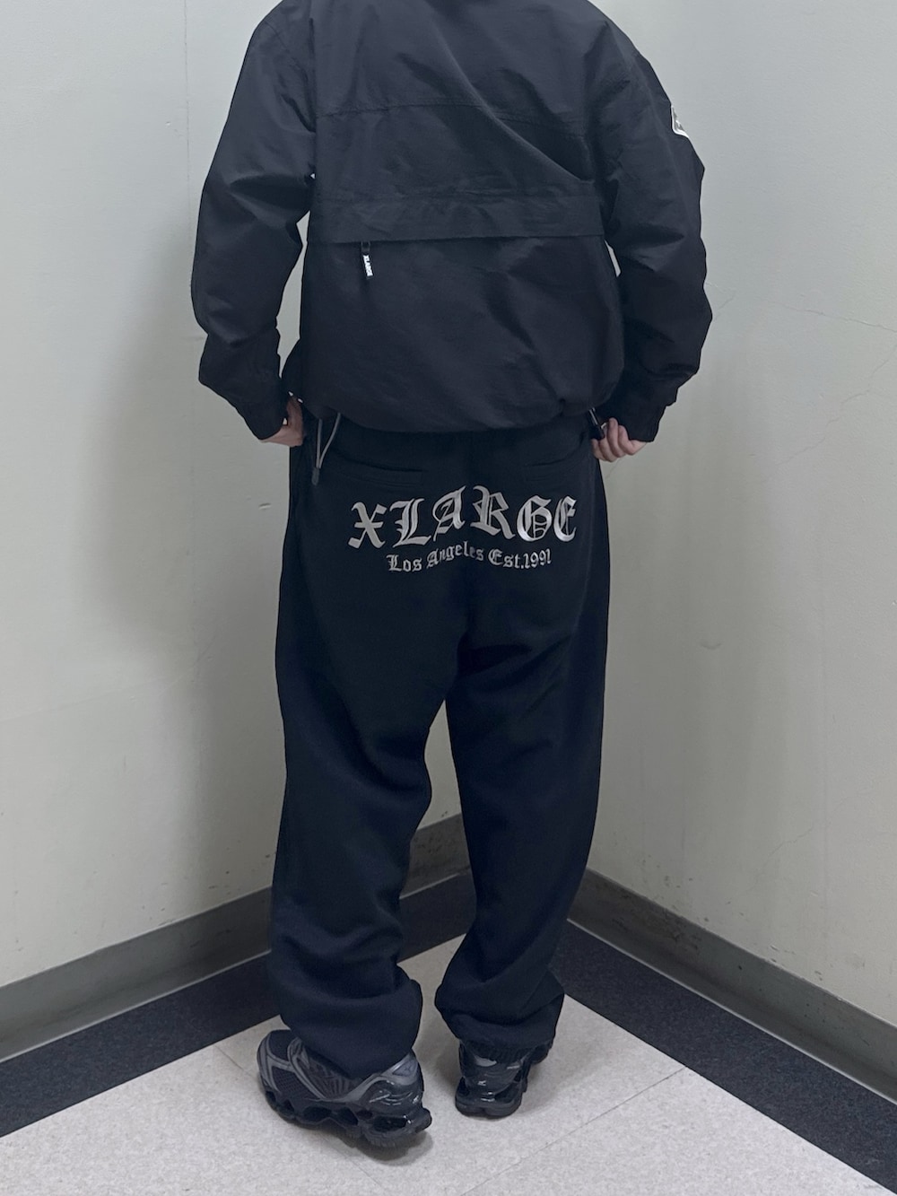 ブラック系のナイロンジャケット、ブラック系のバックパック/リュック、ブラック系のスウェットパンツを着用したメンズの冬コーディネートの3枚目の写真