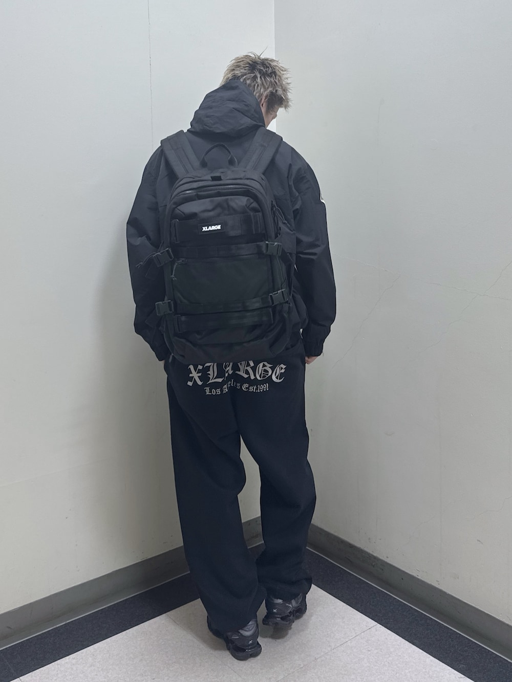 ブラック系のナイロンジャケット、ブラック系のバックパック/リュック、ブラック系のスウェットパンツを着用したメンズの冬コーディネートの2枚目の写真