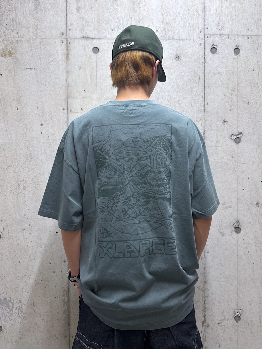 グリーン系のTシャツ/カットソー、ブラック系のデニムパンツ、グリーン系のキャップを着用したメンズの夏コーディネートの3枚目の写真