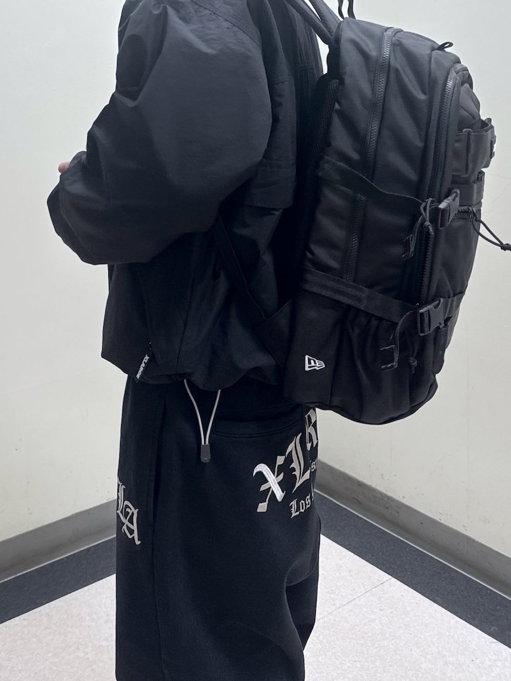 ブラック系のナイロンジャケット、ブラック系のバックパック/リュック、ブラック系のスウェットパンツを着用したメンズの冬コーディネートの4枚目の写真