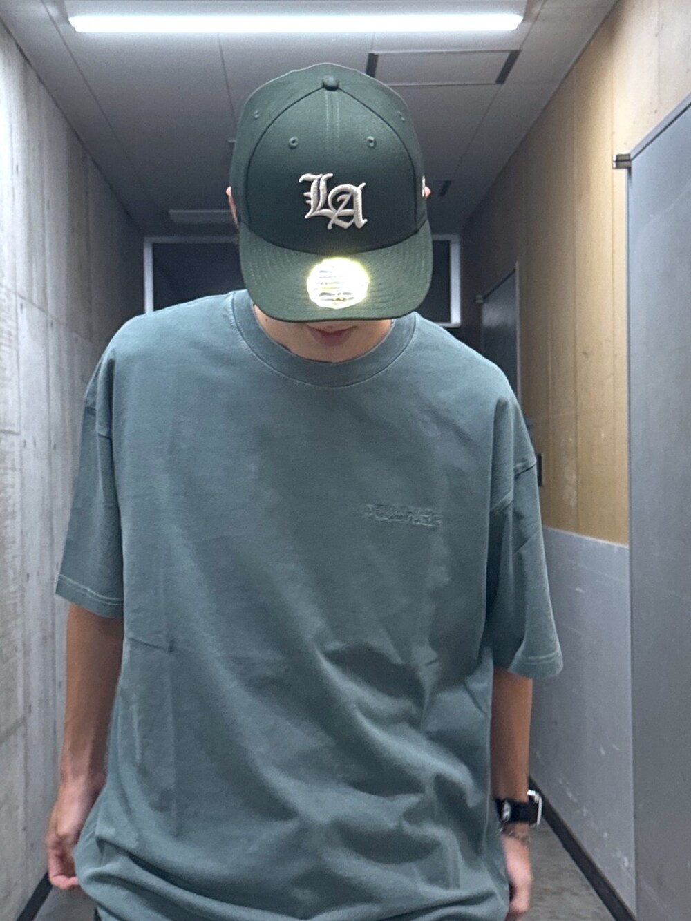 グリーン系のTシャツ/カットソー、ブラック系のデニムパンツ、グリーン系のキャップを着用したメンズの夏コーディネートの4枚目の写真