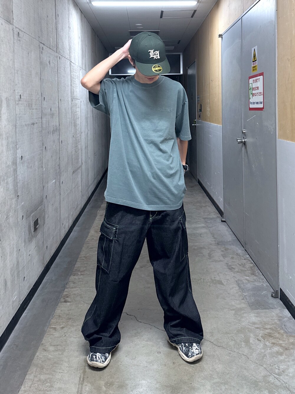 グリーン系のTシャツ/カットソー、ブラック系のデニムパンツ、グリーン系のキャップを着用したメンズの夏コーディネートの2枚目の写真