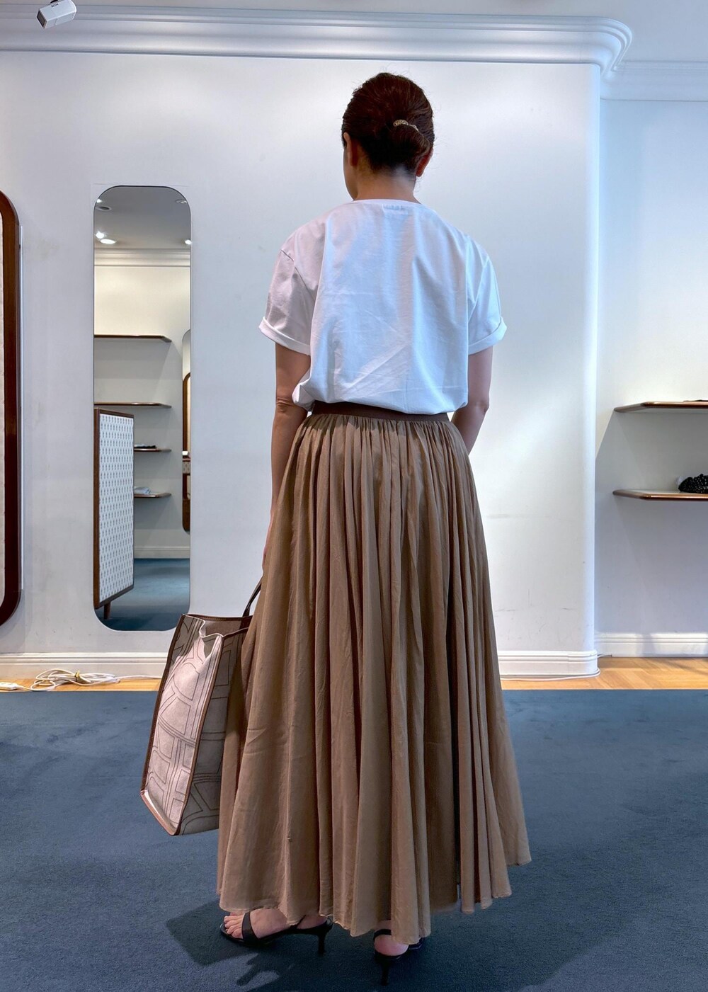 ベージュ系のトートバッグ、ブラック系のサンダル、ホワイト系のTシャツ/カットソーを着用したレディースの夏コーディネートの3枚目の写真