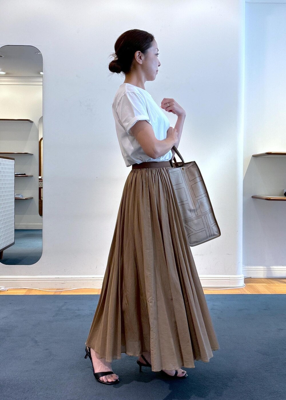 ベージュ系のトートバッグ、ブラック系のサンダル、ホワイト系のTシャツ/カットソーを着用したレディースの夏コーディネートの4枚目の写真