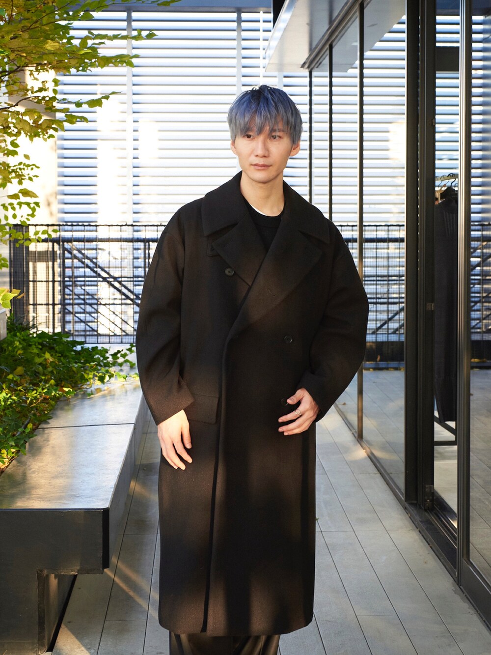 ブラック系のステンカラーコートを着用したメンズの秋コーディネートの4枚目の写真
