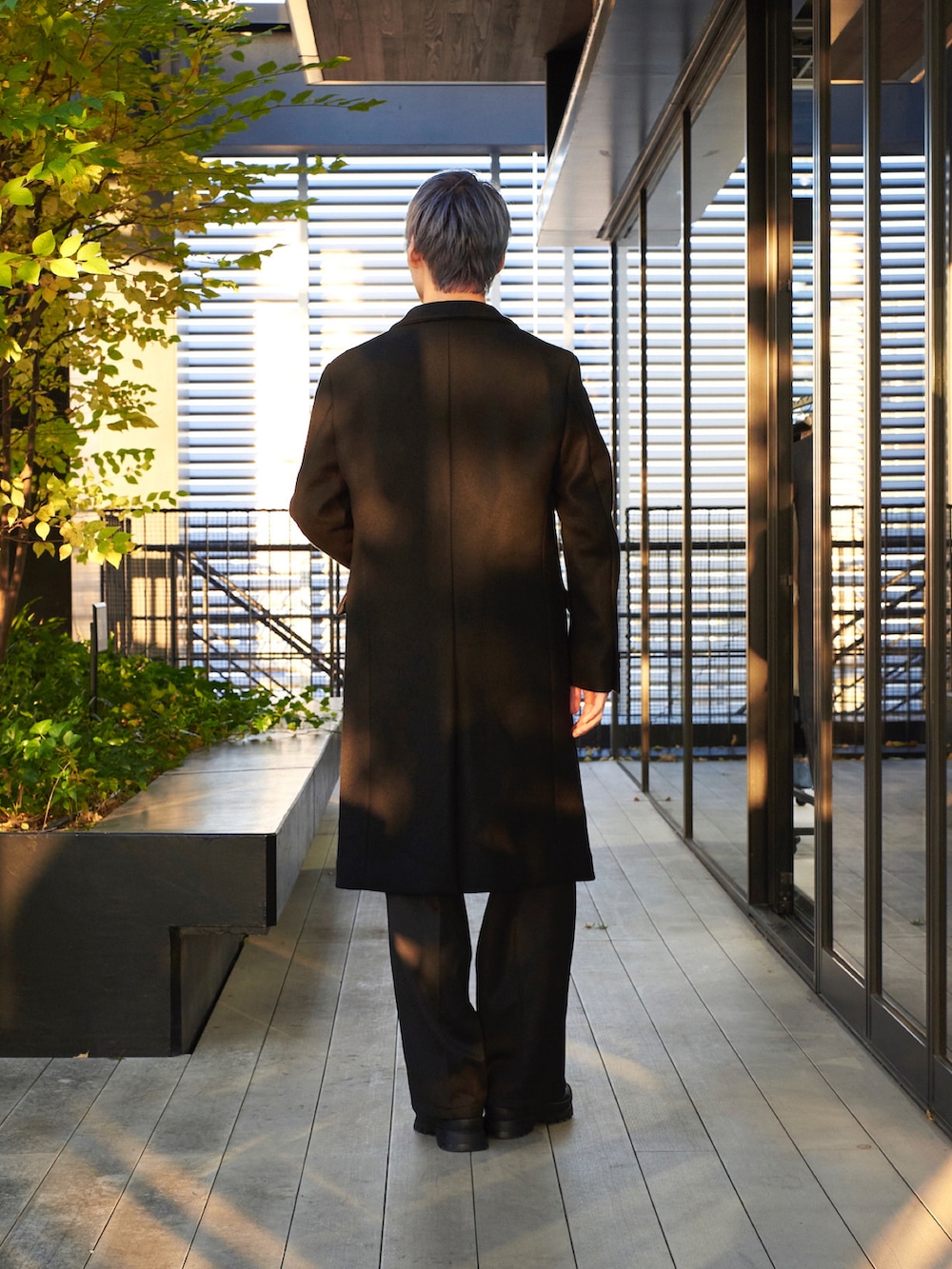 ブラック系のチェスターコートを着用したメンズの秋コーディネートの3枚目の写真