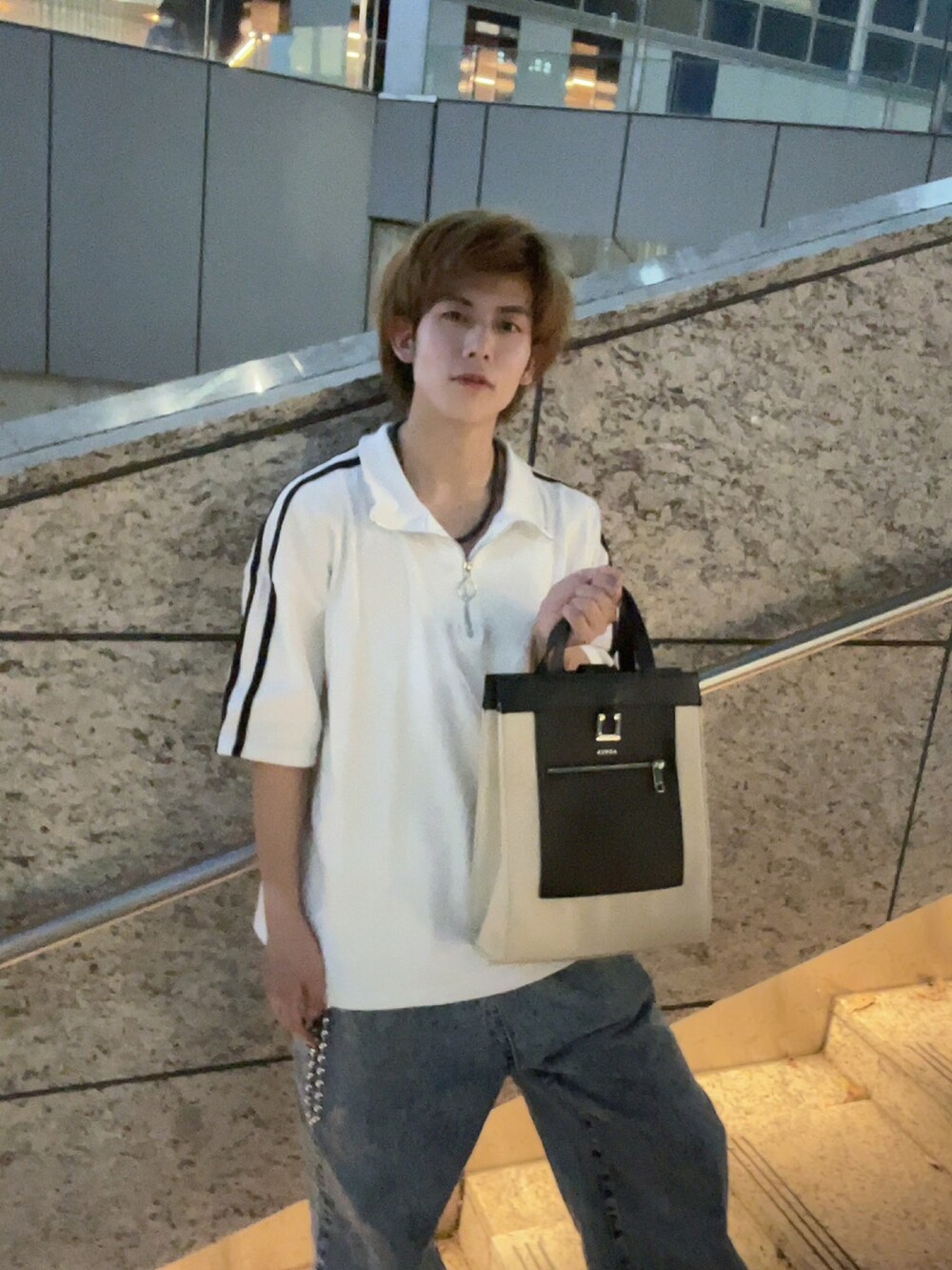 ベージュ系のトートバッグ、ホワイト系のTシャツ/カットソー、ブルー系のデニムパンツを着用したメンズの秋コーディネートの2枚目の写真