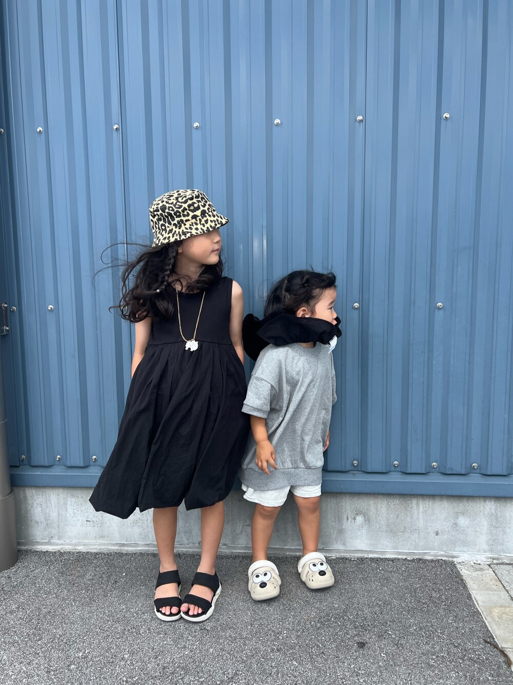 ブラック系のワンピース、グレー系のTシャツ/カットソー、ベージュ系のサンダルを着用したキッズの夏コーディネートの3枚目の写真