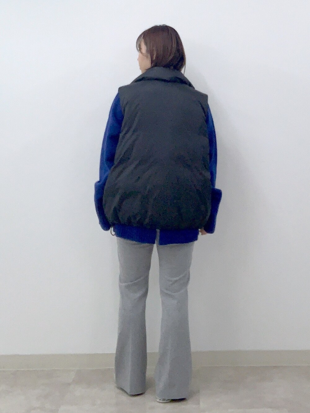 ブラック系のダウンベスト、ブルー系のニット/セーター、グレー系のその他パンツを着用したレディースの秋コーディネートの2枚目の写真