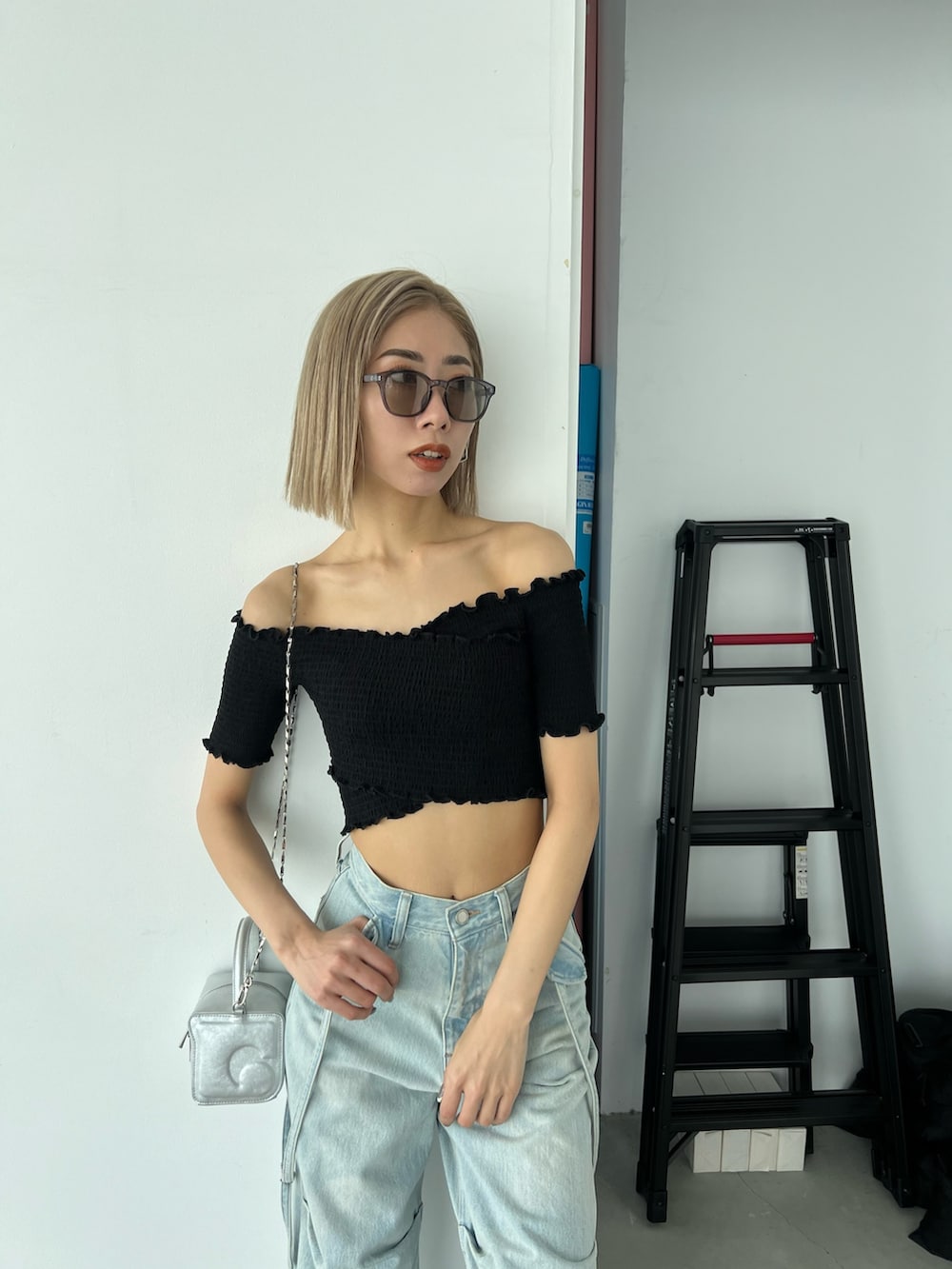 ブルー系のデニムパンツ、ブラック系のTシャツ/カットソー、シルバー系のハンドバッグを着用したレディースの夏コーディネートの4枚目の写真