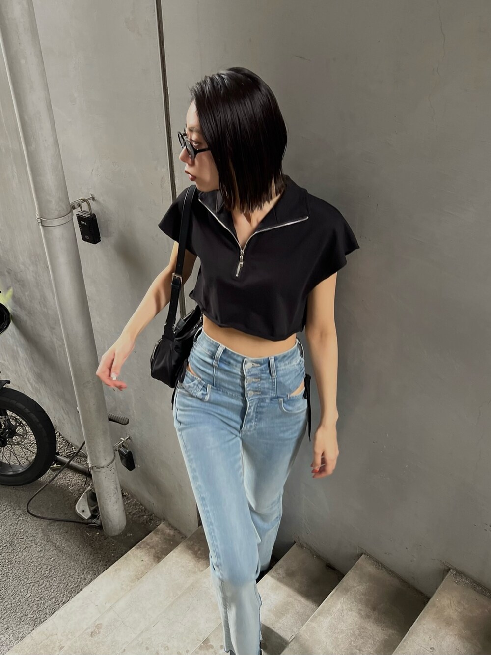 ブルー系のデニムパンツ、ブラック系のTシャツ/カットソー、ブラック系のサンダルを着用したレディースの夏コーディネートの2枚目の写真