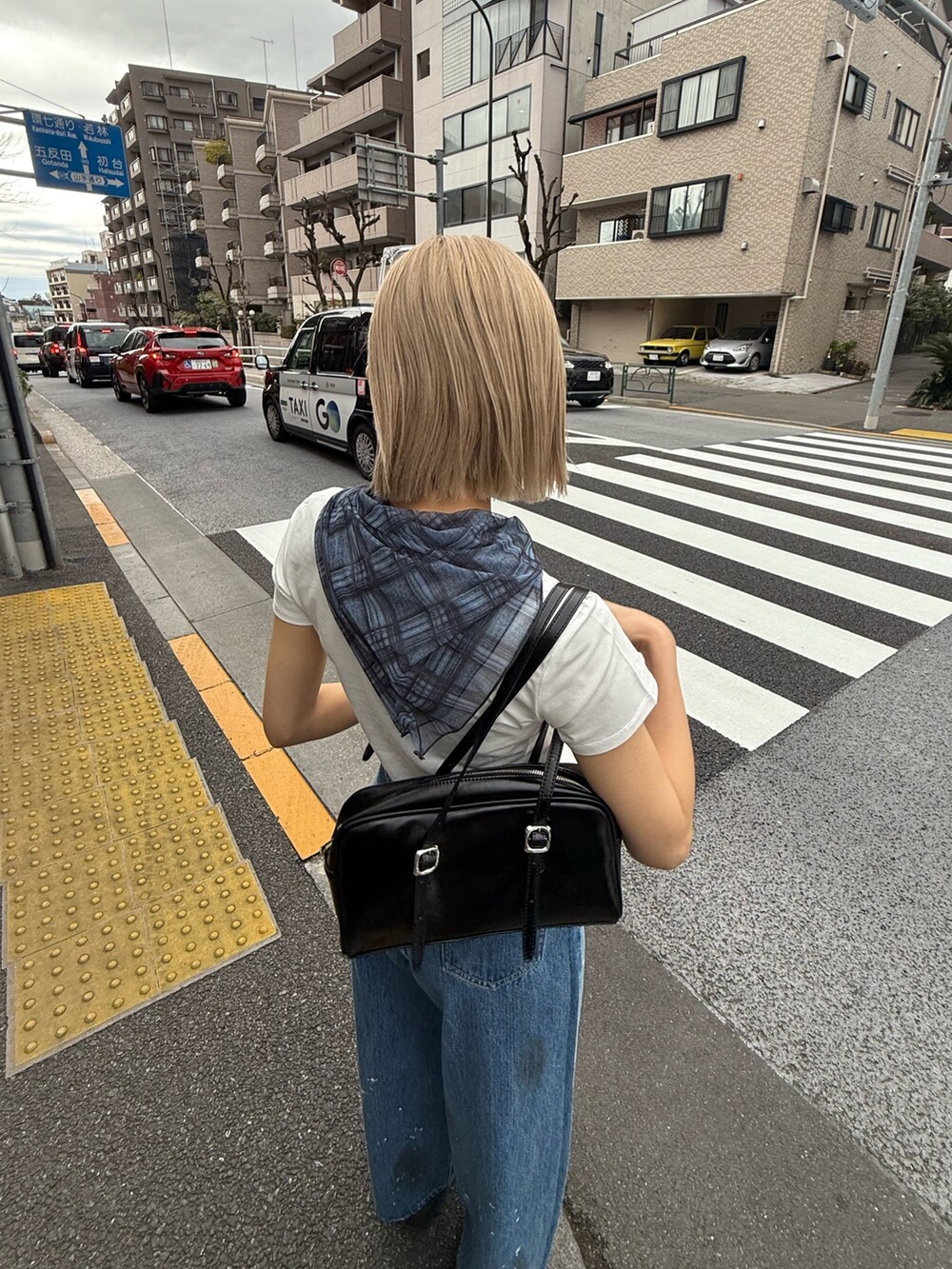 ブルー系のデニムパンツ、ブラック系のハンドバッグ、ブラック系のサンダルを着用したレディースの春コーディネートの5枚目の写真