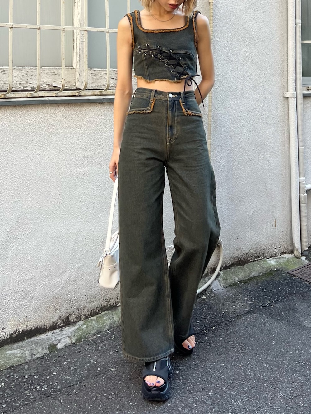 ブルー系のデニムパンツ、ブルー系のタンクトップ、ブラック系のサンダルを着用したレディースの春コーディネートの4枚目の写真