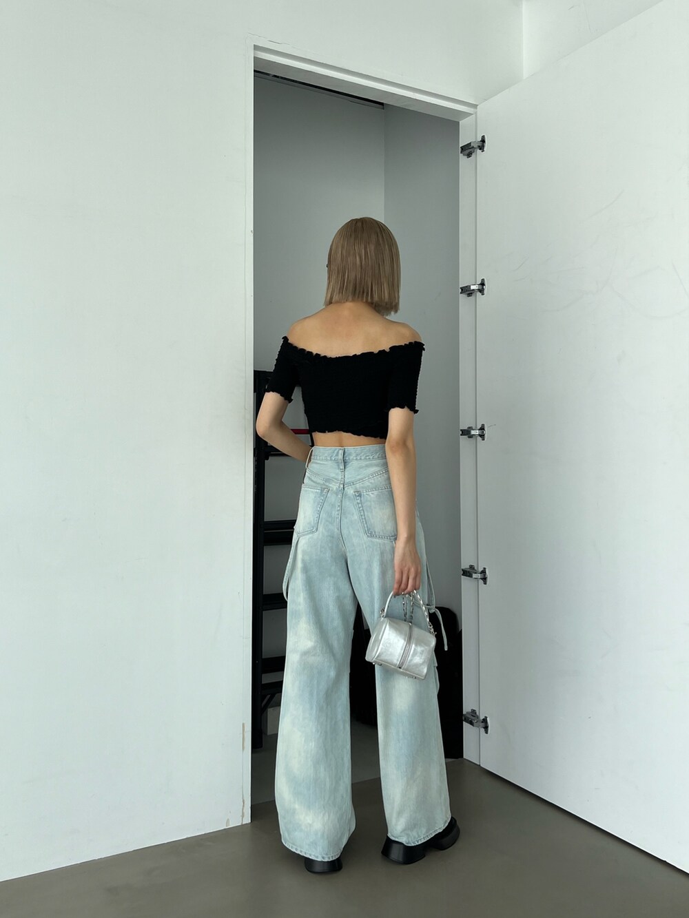 ブルー系のデニムパンツ、ブラック系のTシャツ/カットソー、シルバー系のハンドバッグを着用したレディースの夏コーディネートの3枚目の写真