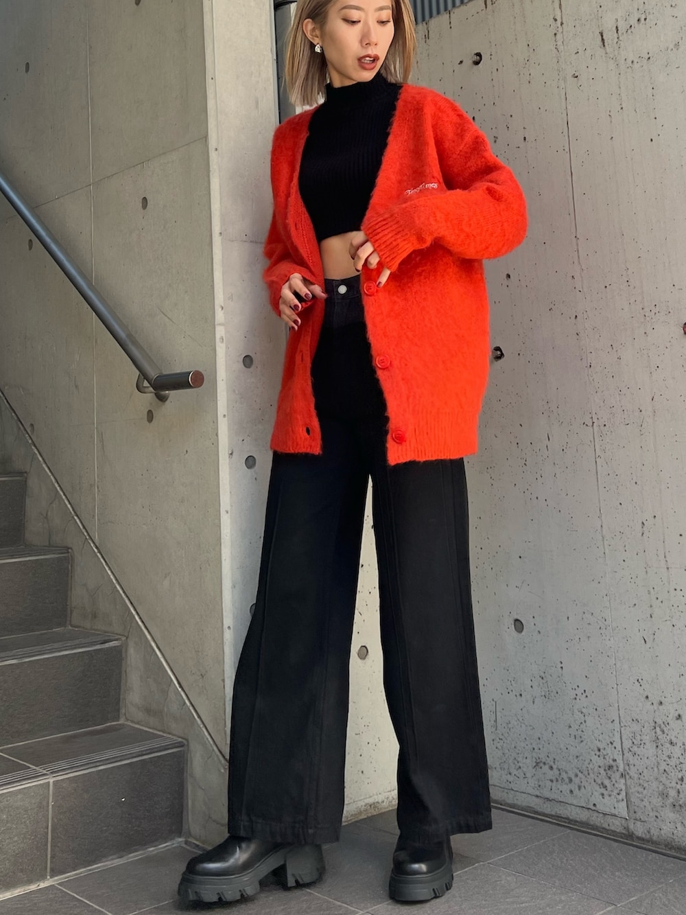 ブラック系のデニムパンツ、ブラック系のブーツ、オレンジ系のカーディガン/ボレロを着用したレディースの秋コーディネートの2枚目の写真