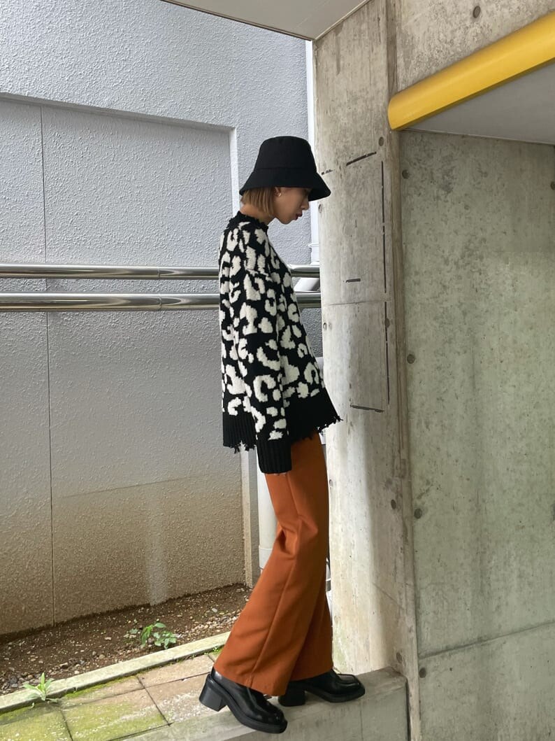 オレンジ系のその他パンツ、ブラック系のブーツ、ブラック系のニット/セーターを着用したレディースの秋コーディネートの2枚目の写真