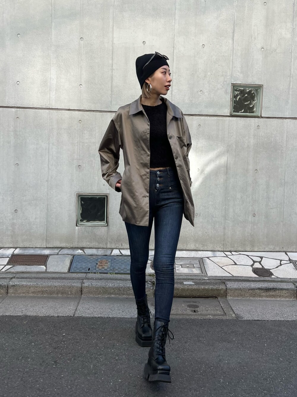 ブルー系のデニムパンツ、ブラック系のブーツ、ブラウン系のナイロンジャケットを着用したレディースの春コーディネートの5枚目の写真