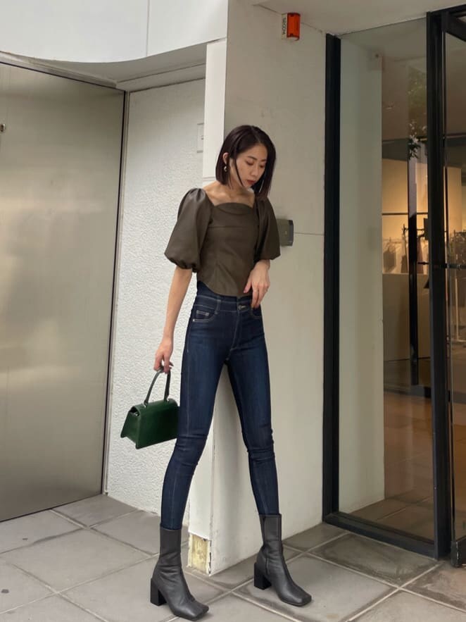 ブラウン系のTシャツ/カットソー、グリーン系のハンドバッグ、ブルー系のデニムパンツを着用したレディースの秋コーディネートの2枚目の写真