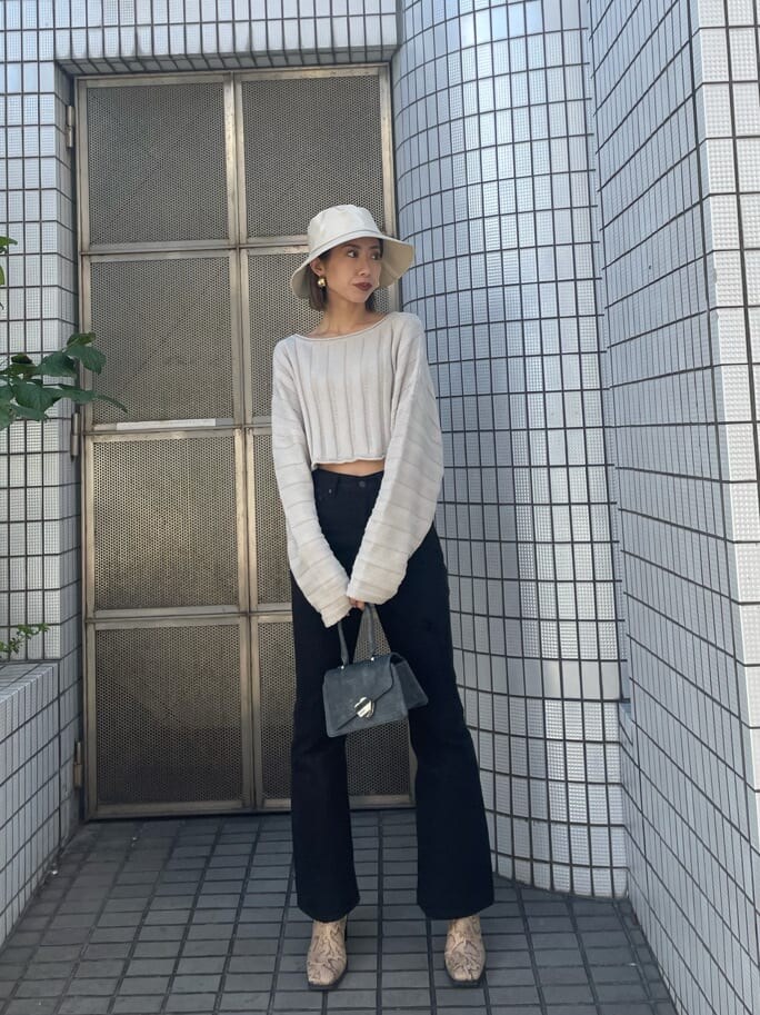 ホワイト系のニット/セーター、ブラック系のデニムパンツ、ホワイト系のハットを着用したレディースの冬コーディネートの2枚目の写真