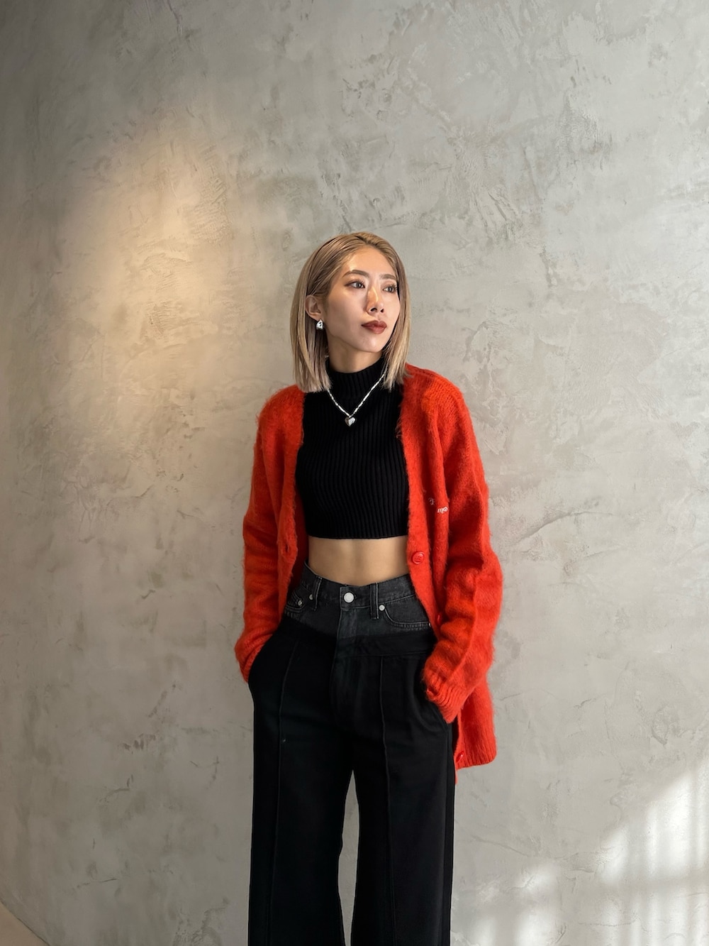 ブラック系のデニムパンツ、ブラック系のブーツ、オレンジ系のカーディガン/ボレロを着用したレディースの秋コーディネートの3枚目の写真