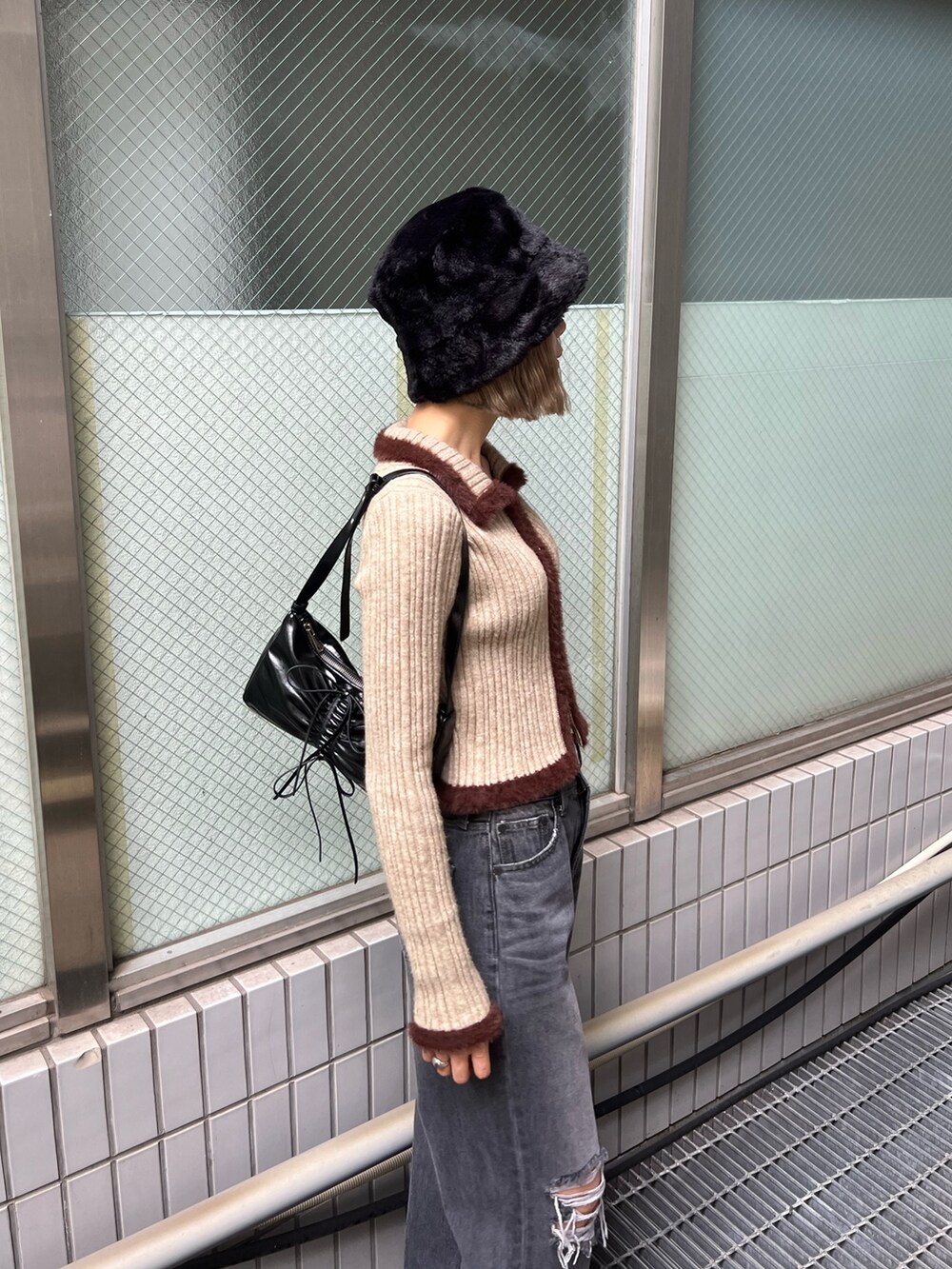 グレー系のデニムパンツ、ブラック系のローファー、ブラック系のショルダーバッグを着用したレディースの秋コーディネートの5枚目の写真