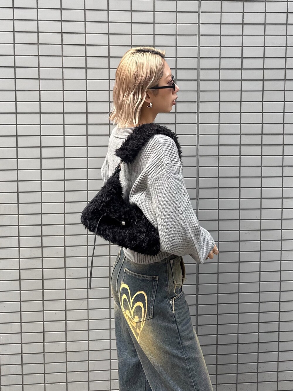 グレー系のニット/セーター、ブルー系のデニムパンツ、ブラック系のショルダーバッグを着用したレディースの冬コーディネートの6枚目の写真