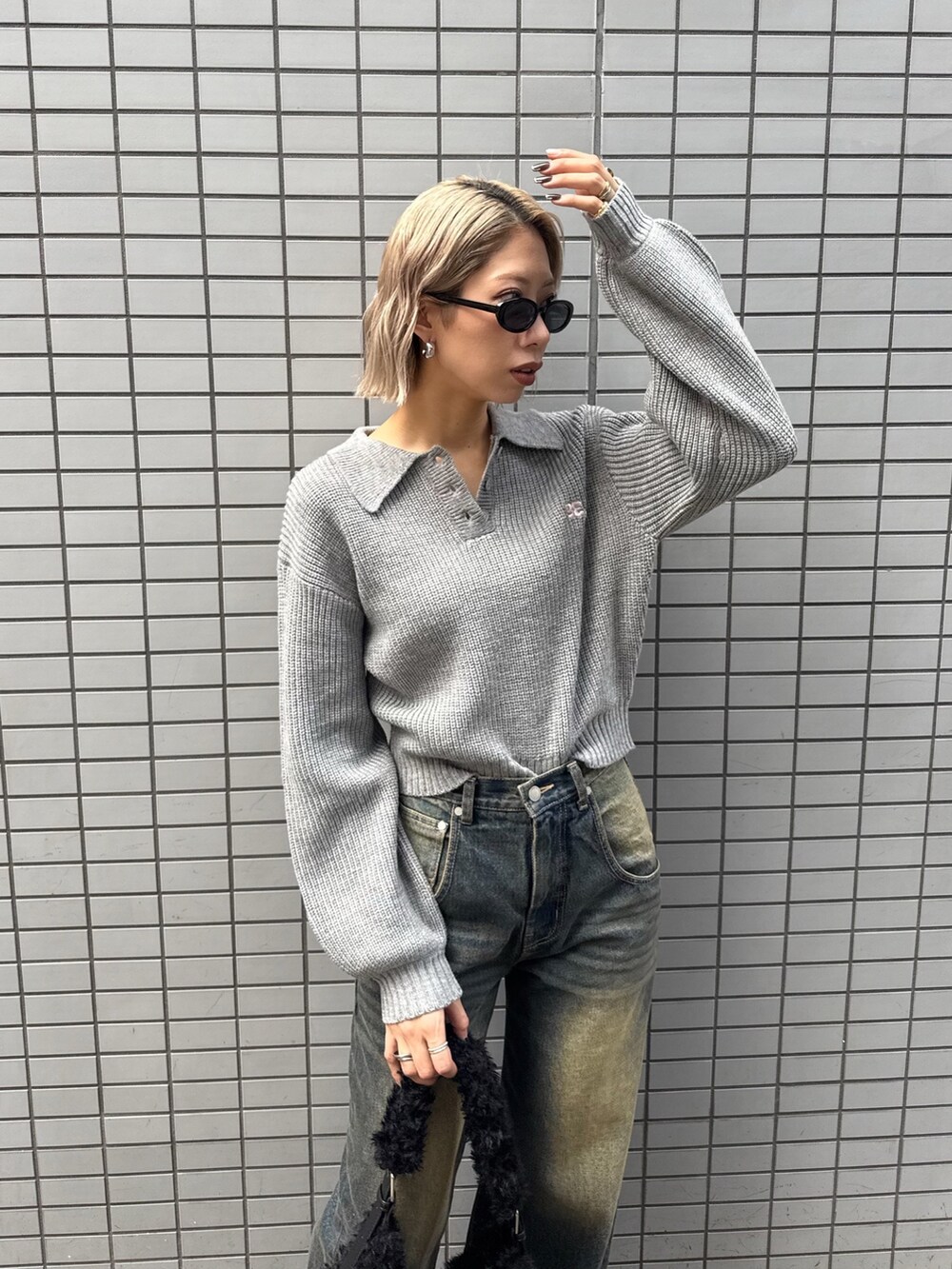 グレー系のニット/セーター、ブルー系のデニムパンツ、ブラック系のショルダーバッグを着用したレディースの冬コーディネートの4枚目の写真