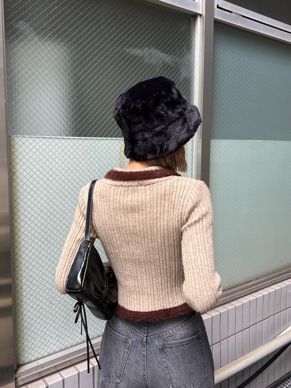 グレー系のデニムパンツ、ブラック系のローファー、ブラック系のショルダーバッグを着用したレディースの秋コーディネートの4枚目の写真