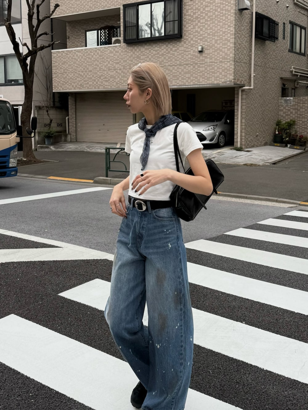 ブルー系のデニムパンツ、ブラック系のハンドバッグ、ブラック系のサンダルを着用したレディースの春コーディネートの2枚目の写真