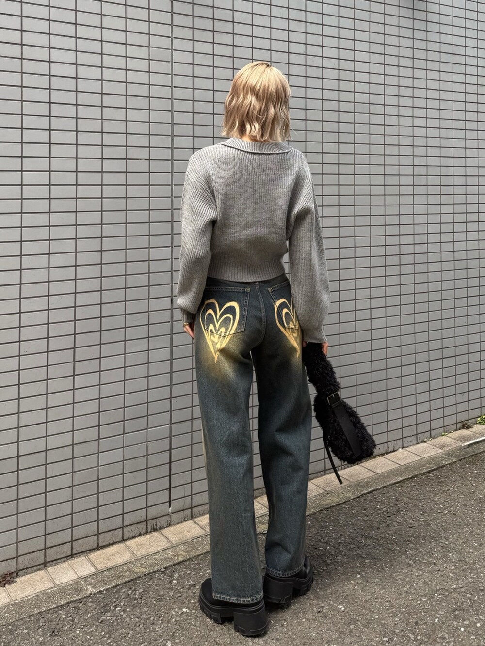 グレー系のニット/セーター、ブルー系のデニムパンツ、ブラック系のショルダーバッグを着用したレディースの冬コーディネートの3枚目の写真