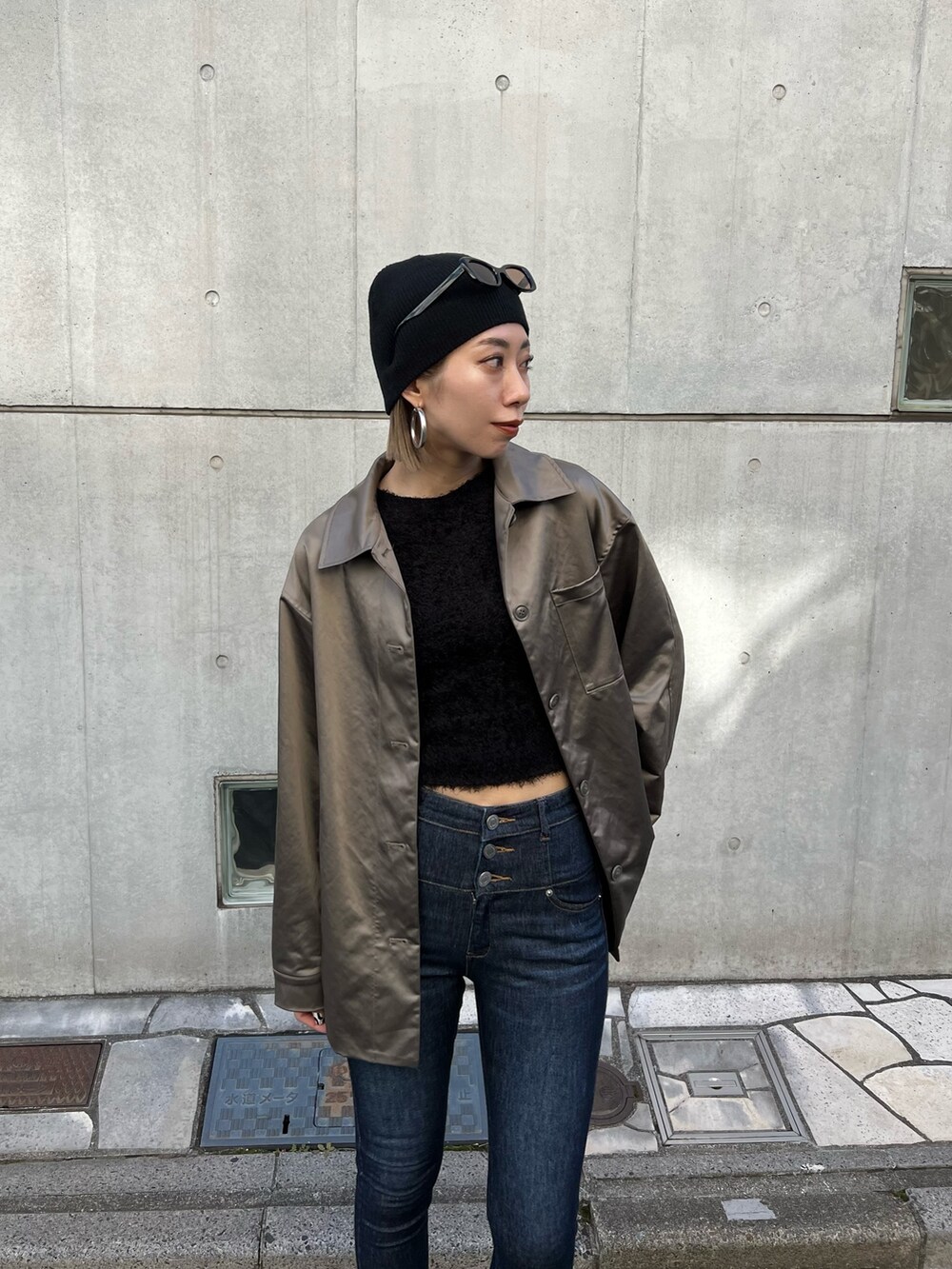 ブルー系のデニムパンツ、ブラック系のブーツ、ブラウン系のナイロンジャケットを着用したレディースの春コーディネートの4枚目の写真