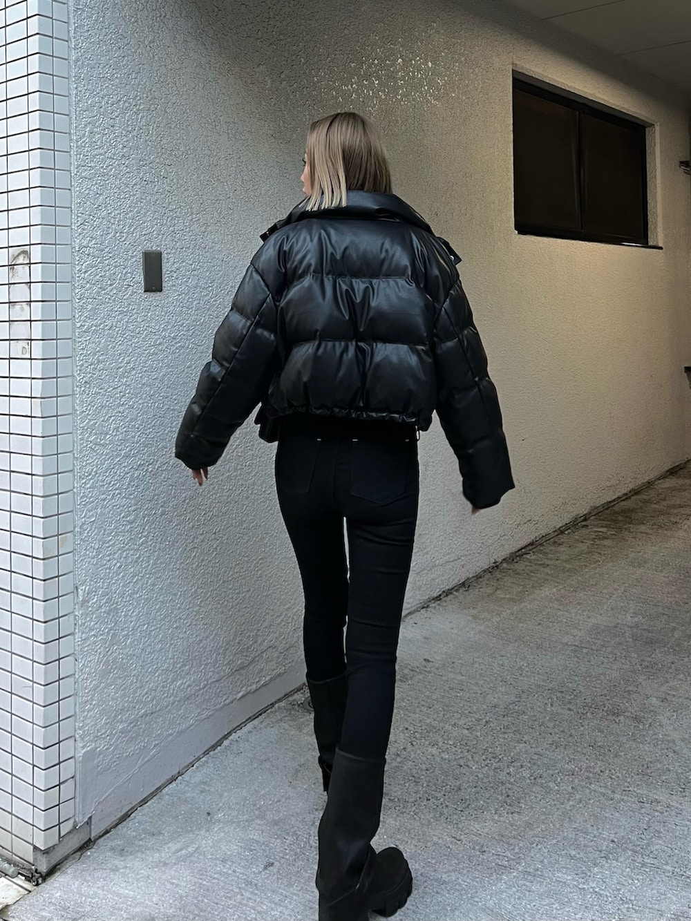 ブラック系のデニムパンツ、ブラック系のブーツ、ブラック系のダウンジャケット/コートを着用したレディースの冬コーディネートの3枚目の写真