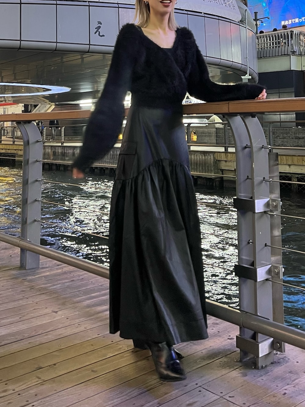 ブラック系のスカート、ブラック系のニット/セーター、ブラック系のブーツを着用したレディースの秋コーディネートの2枚目の写真