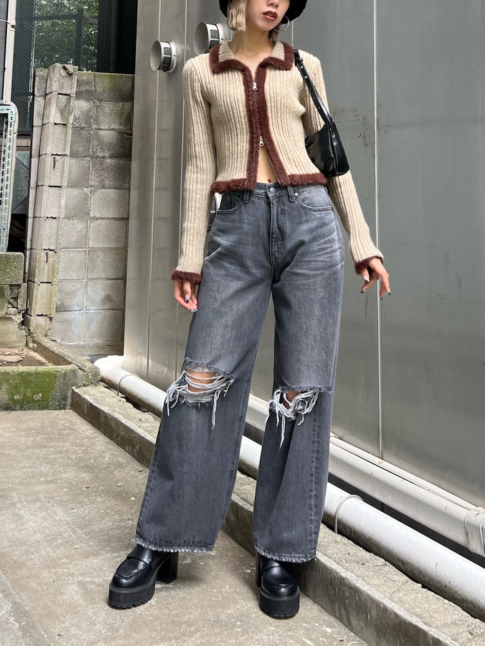 グレー系のデニムパンツ、ブラック系のローファー、ブラック系のショルダーバッグを着用したレディースの秋コーディネートの2枚目の写真