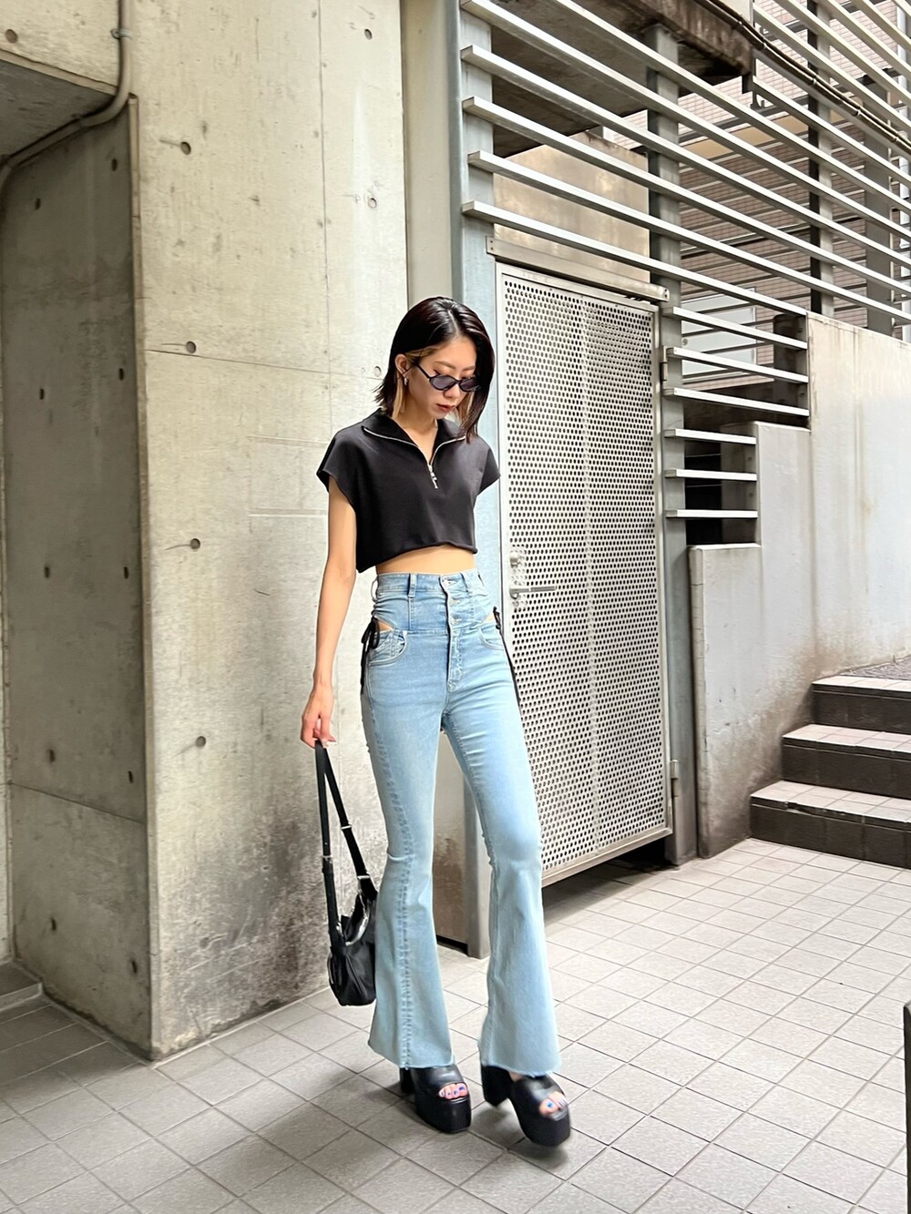 ブルー系のデニムパンツ、ブラック系のTシャツ/カットソー、ブラック系のサンダルを着用したレディースの夏コーディネートの6枚目の写真