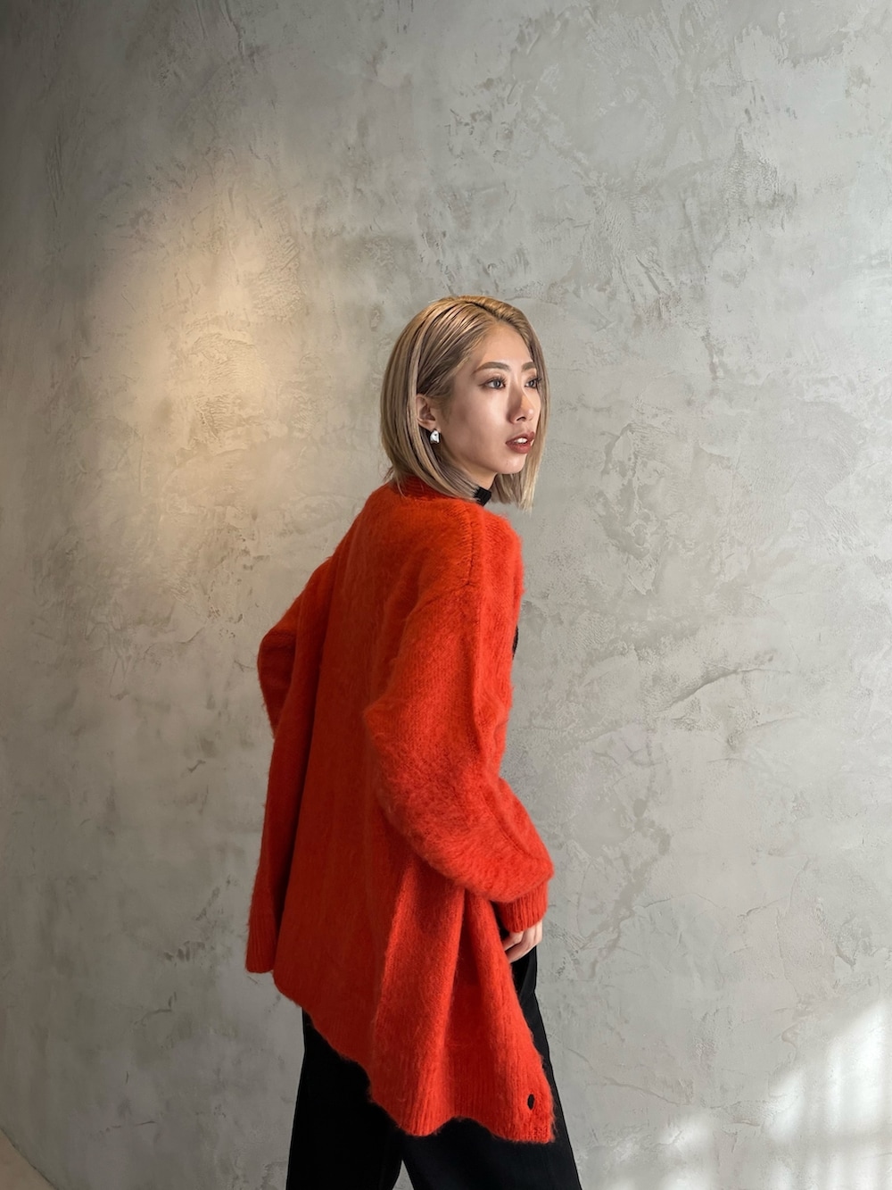 ブラック系のデニムパンツ、ブラック系のブーツ、オレンジ系のカーディガン/ボレロを着用したレディースの秋コーディネートの4枚目の写真