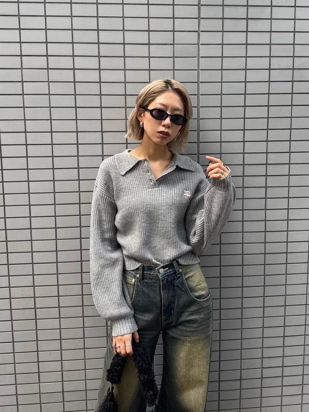 グレー系のニット/セーター、ブルー系のデニムパンツ、ブラック系のショルダーバッグを着用したレディースの冬コーディネートの2枚目の写真