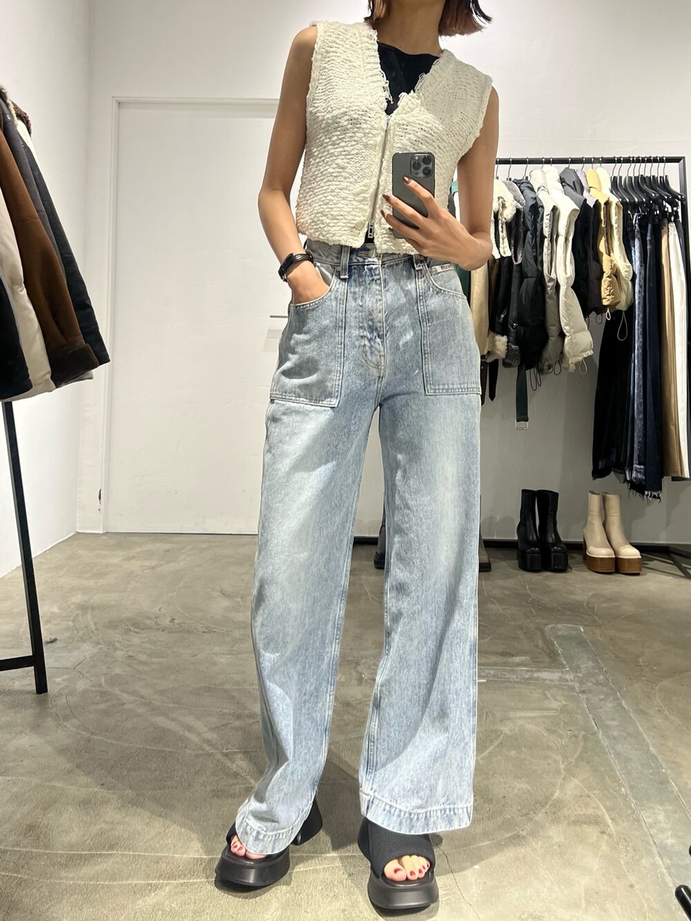 ブルー系のデニムパンツ、ホワイト系のベスト、ブラック系のサンダルを着用したレディースの夏コーディネートの2枚目の写真