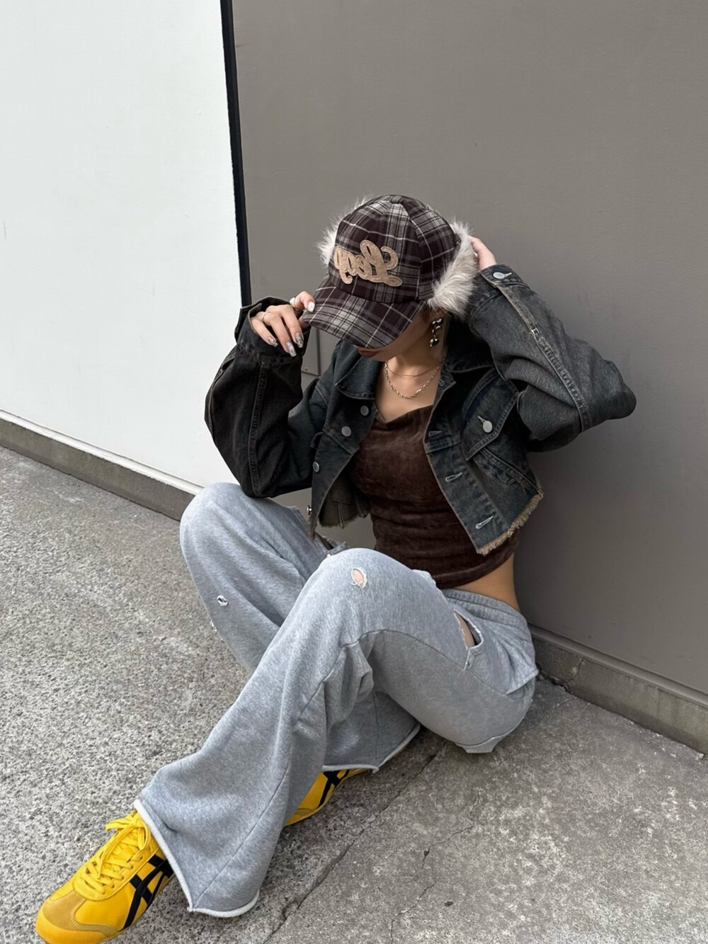ブルー系のデニムジャケット、グレー系のスウェットパンツ、ベージュ系のキャップを着用したレディースの秋コーディネートの2枚目の写真