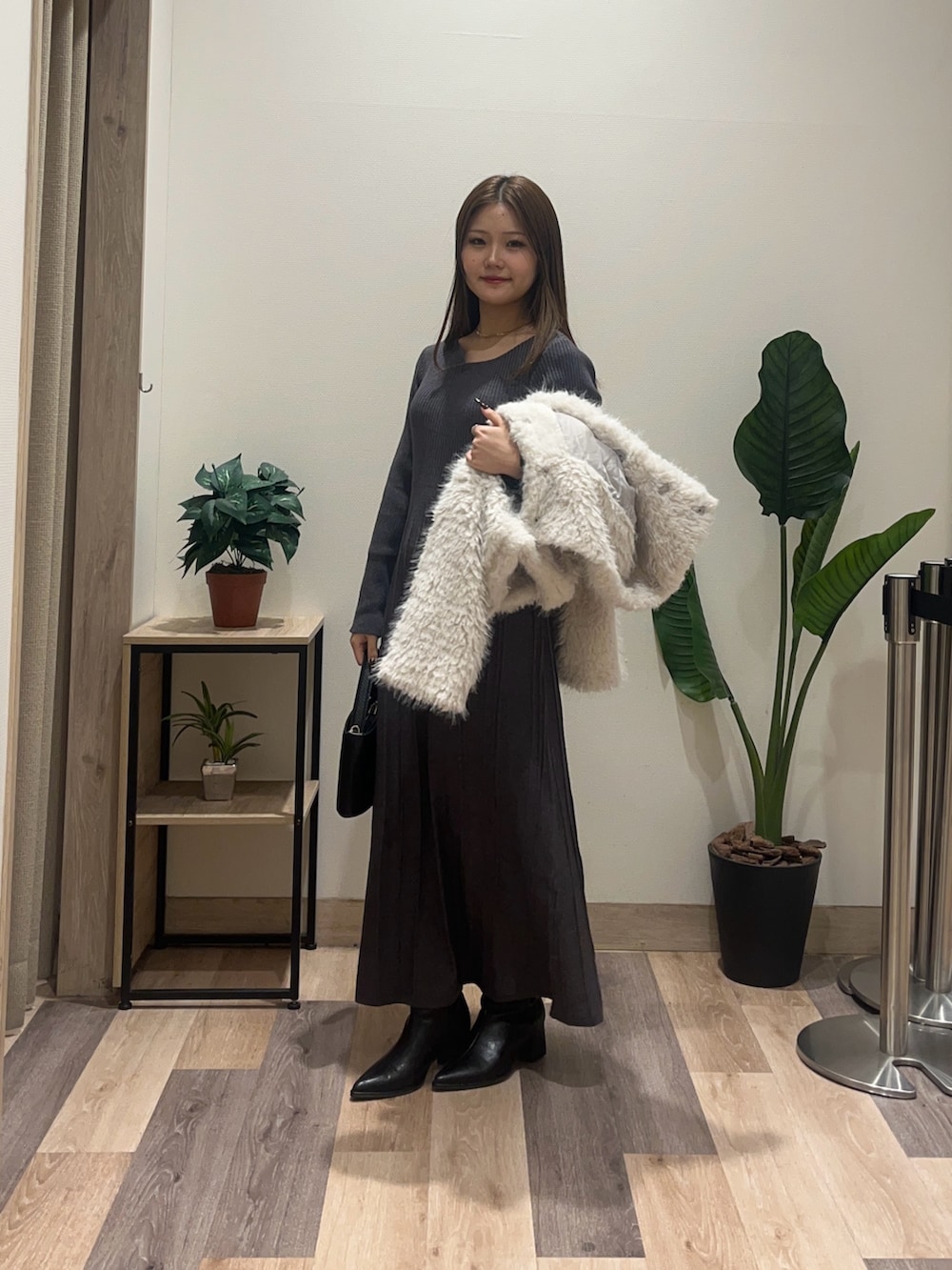 グレー系のワンピース、ホワイト系のブルゾン、ブラック系のブーツを着用したレディースの冬コーディネートの5枚目の写真