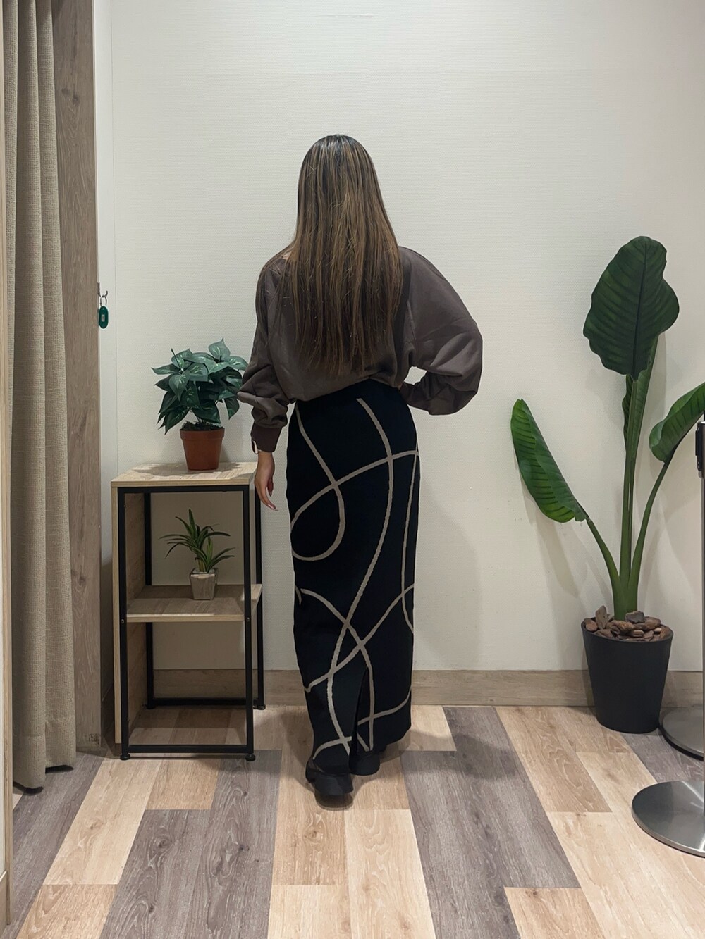 ブラック系のスカート、ブラウン系のTシャツ/カットソー、ブラック系のブーツを着用したレディースの秋コーディネートの4枚目の写真