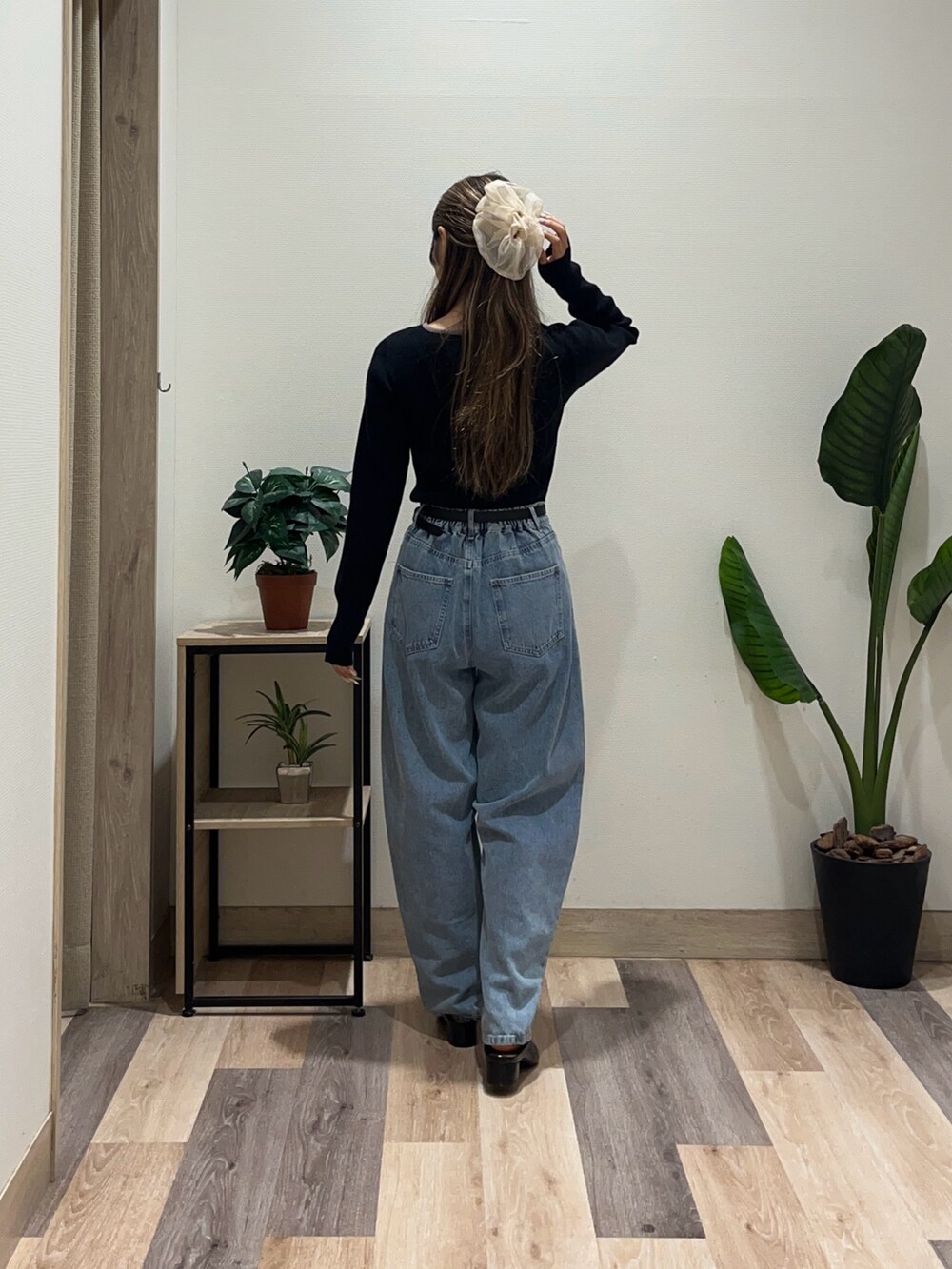 ブルー系のデニムパンツ、ブラック系のニット/セーター、ブラック系のベルトを着用したレディースの秋コーディネートの3枚目の写真