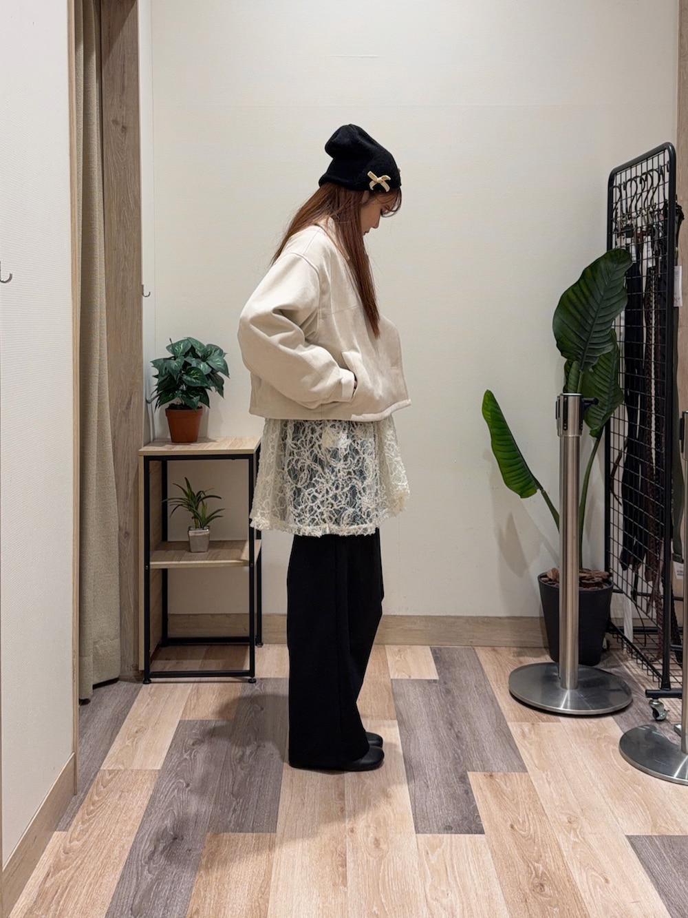 イエロー系のブルゾン、ブラック系のブーツ、ホワイト系のチュニックを着用したレディースの冬コーディネートの3枚目の写真