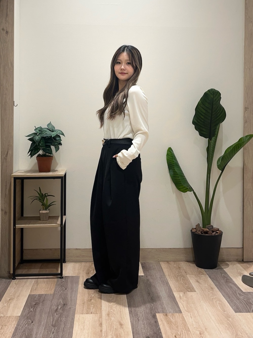 ホワイト系のTシャツ/カットソー、ブラック系のスラックス、ブラック系のブーツを着用したレディースの秋コーディネートの4枚目の写真