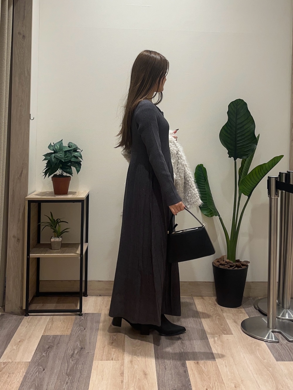 グレー系のワンピース、ホワイト系のブルゾン、ブラック系のブーツを着用したレディースの冬コーディネートの3枚目の写真