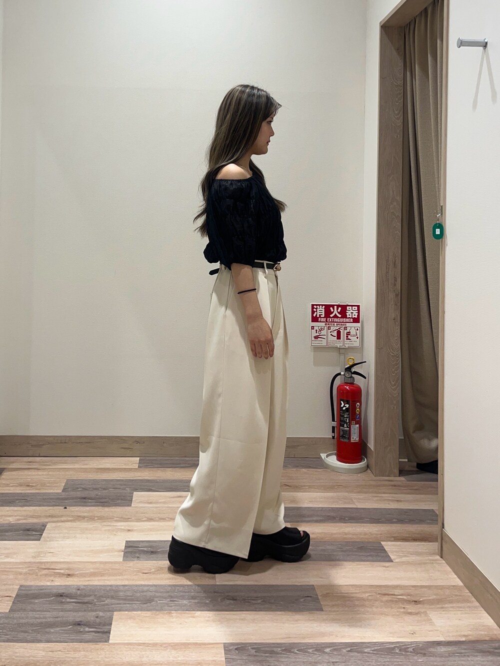 ホワイト系のスラックス、ブラック系のシャツ/ブラウス、ブラック系のベルトを着用したレディースの夏コーディネートの2枚目の写真