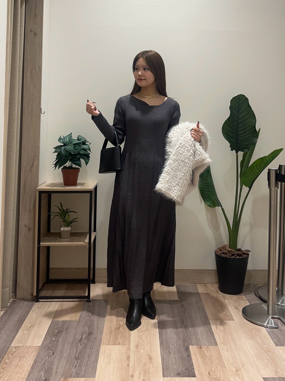 グレー系のワンピース、ホワイト系のブルゾン、ブラック系のブーツを着用したレディースの冬コーディネートの2枚目の写真